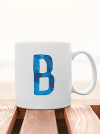 blue initial letter coffee mug on the beach