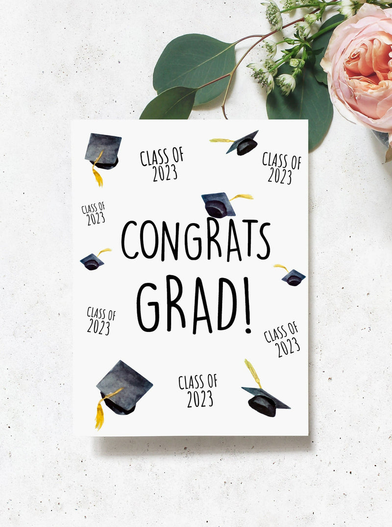 class of 2023 congrats grad graduation card. Graduation hats and class of 2023 arranged all over the face of the card. Black caps and gold tassels.
