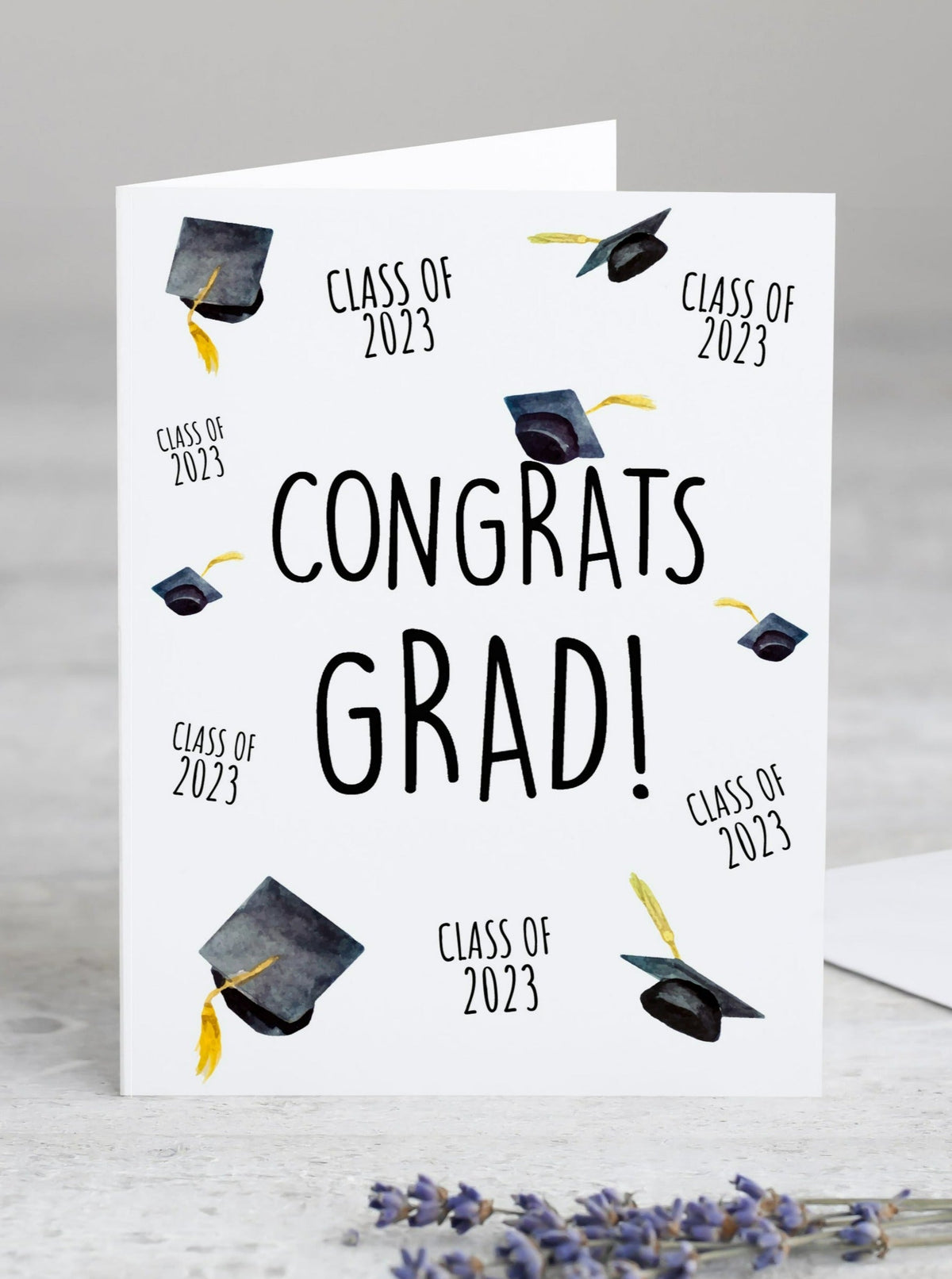 class of 2023 congrats grad graduation card.  Graduation hats and class of 2023 arranged all over the face of the card.  Black caps and gold tassels.