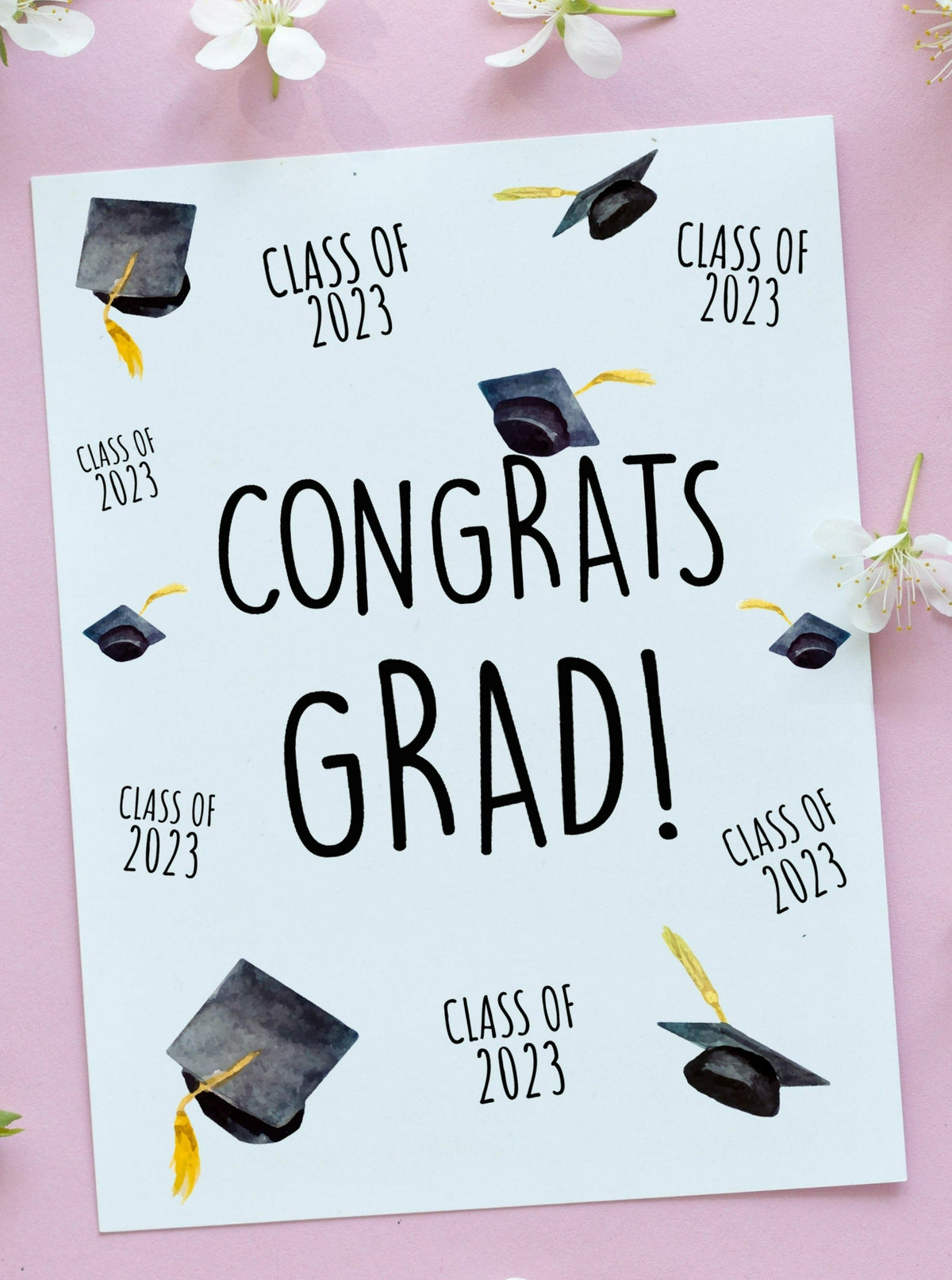 class of 2023 congrats grad graduation card. Graduation hats and class of 2023 arranged all over the face of the card. Black caps and gold tassels.