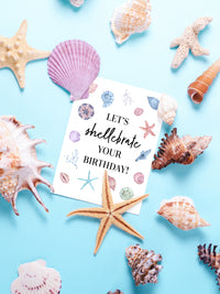 "An artistic depiction of delicate seashells scattered on a sandy beach, accompanied by a vibrant and cheerful birthday card design featuring beach-themed elements, perfect for celebrating a special day by the sea." Light blue pale red, cream colors with Black lettering