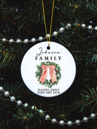 White circular ceramic ornament with the words Our First Christmas As Mr. & Mrs. followed by the family name in the center and the year. There is a wreath under the family name.  Black cursive font.  Ships with gold threaded ornament tie.