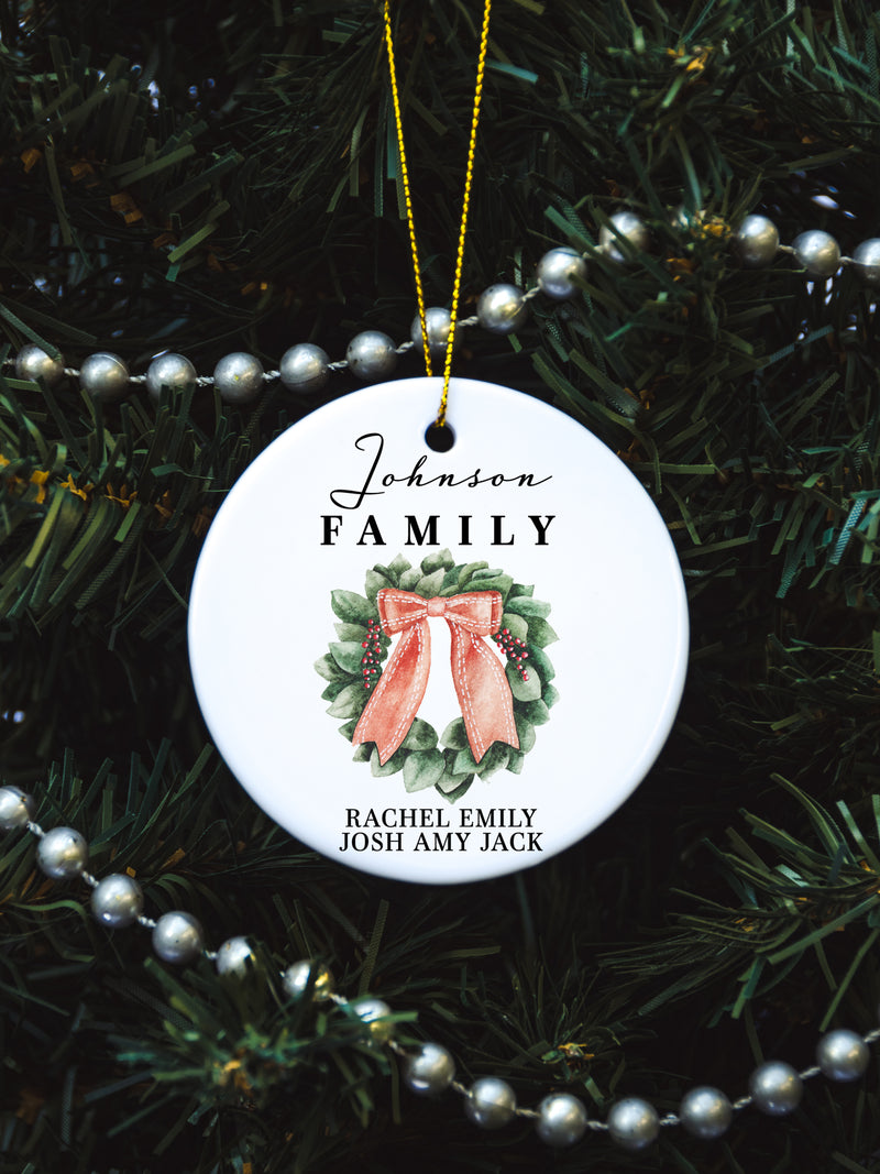White circular ceramic ornament with the words Our First Christmas As Mr. & Mrs. followed by the family name in the center and the year. There is a wreath under the family name.  Black cursive font.  Ships with gold threaded ornament tie.