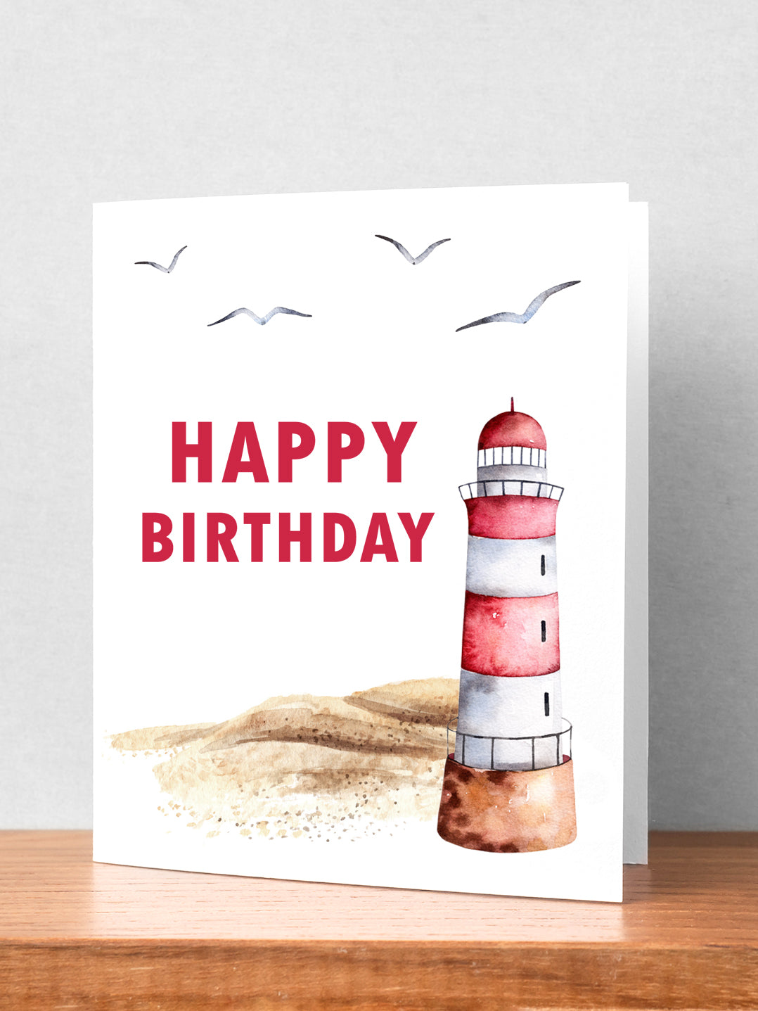 "A picturesque sandy beach with a red and white lighthouse set against a serene coastal backdrop, complemented by a heartfelt Happy Birthday in Red Lettering card design, evoking gratitude and a sense of calm seaside "