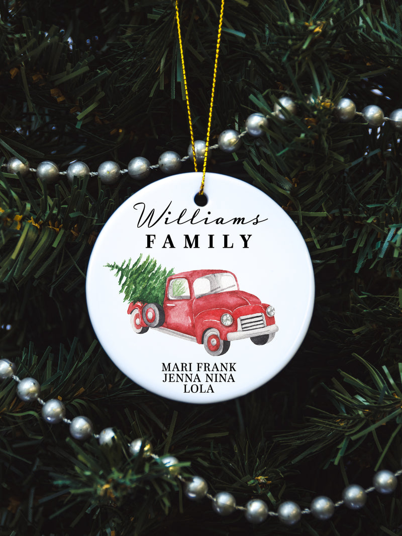 White circular ceramic ornament with the words Our First Christmas As Mr. & Mrs. followed by the family name in the center and the year. There is a red truck and Christmas Tree under name.  Black cursive font.  Ships with gold threaded ornament tie.