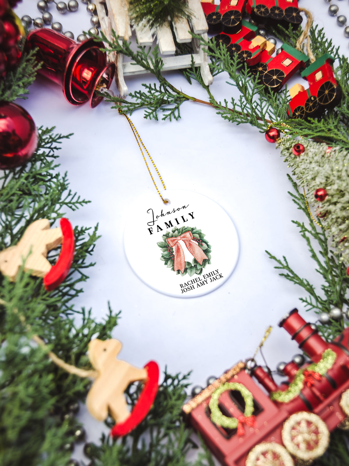White circular ceramic ornament with the words Our First Christmas As Mr. & Mrs. followed by the family name in the center and the year. There is a wreath under the family name.  Black cursive font.  Ships with gold threaded ornament tie.