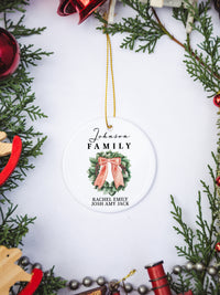 White circular ceramic ornament with the words Our First Christmas As Mr. & Mrs. followed by the family name in the center and the year. There is a wreath under the family name.  Black cursive font.  Ships with gold threaded ornament tie.