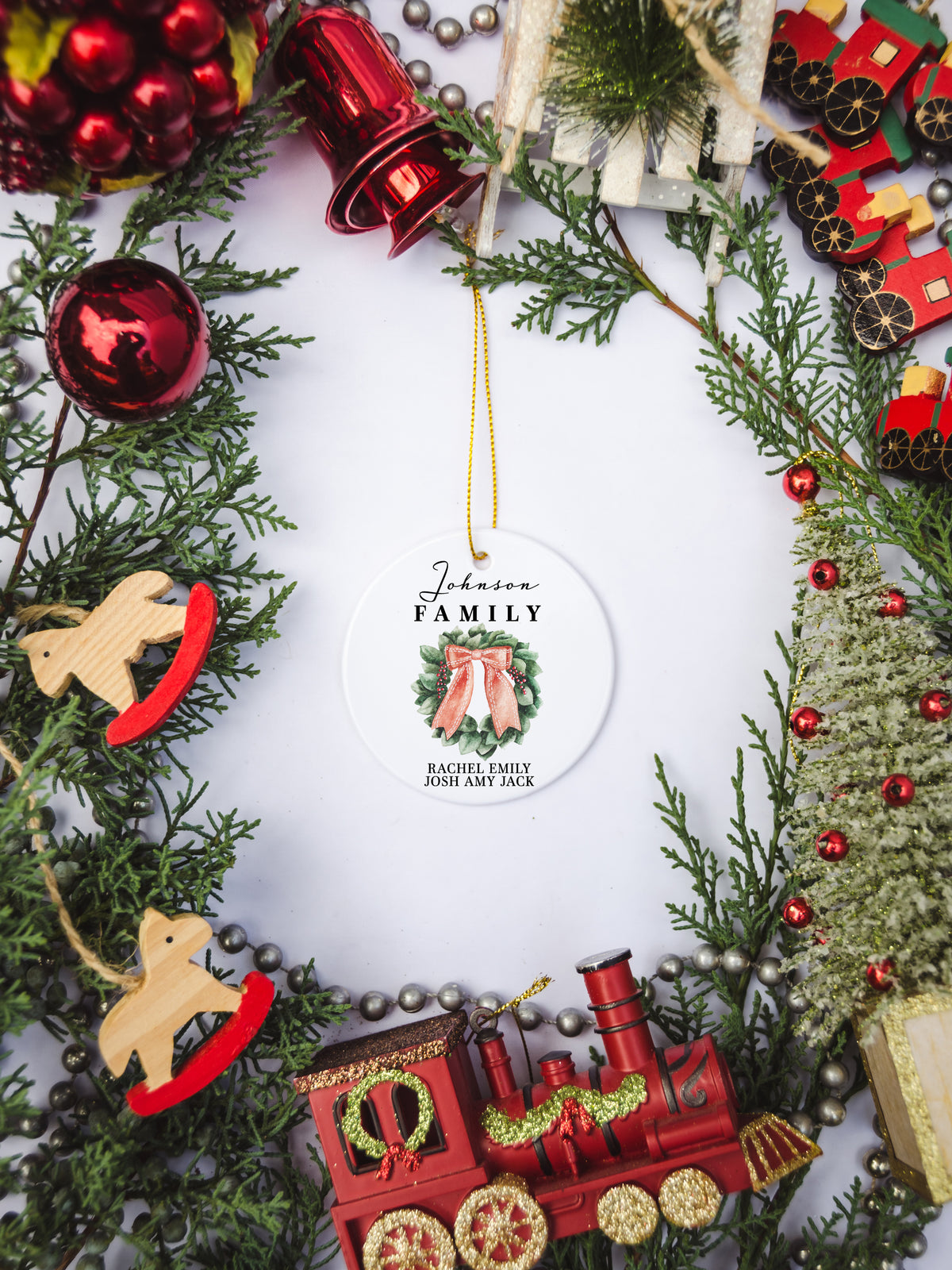 White circular ceramic ornament with the words Our First Christmas As Mr. & Mrs. followed by the family name in the center and the year. There is a wreath under the family name.  Black cursive font.  Ships with gold threaded ornament tie.