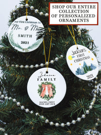 White circular ceramic ornament with the words Our First Christmas As Mr. & Mrs. followed by the family name in the center and the year. There is a wreath under the family name.  Black cursive font.  Ships with gold threaded ornament tie.