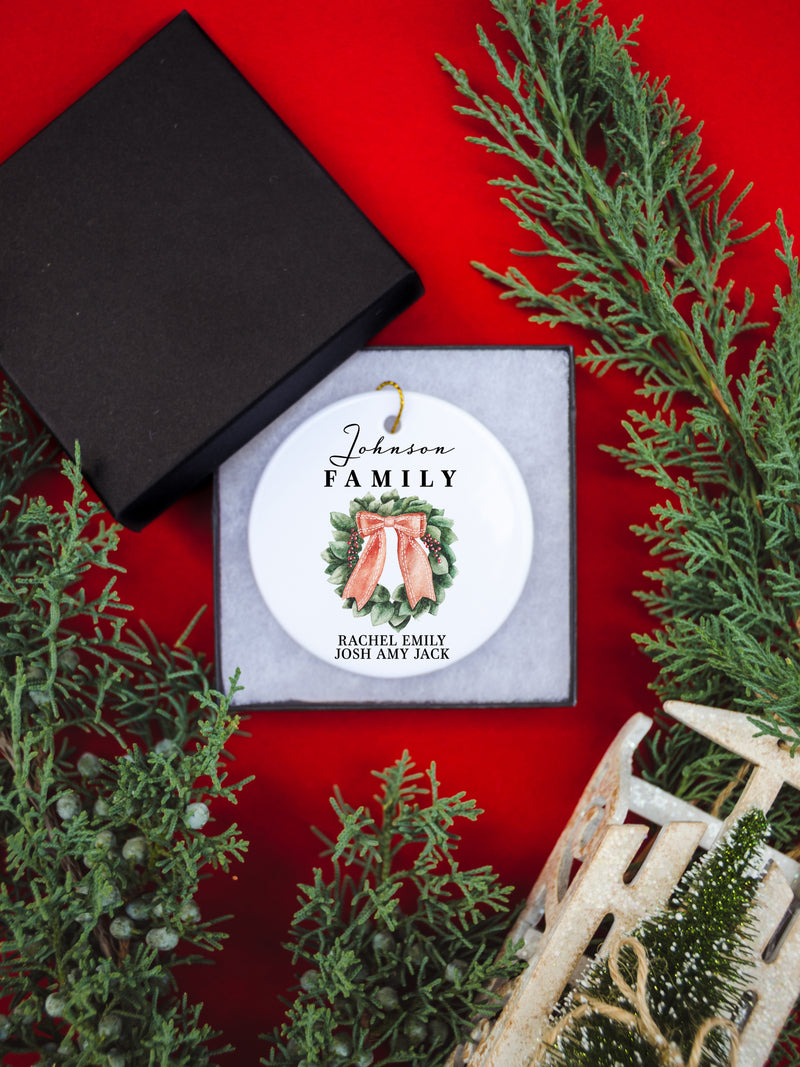 White circular ceramic ornament with the words Our First Christmas As Mr. & Mrs. followed by the family name in the center and the year. There is a wreath under the family name.  Black cursive font.  Ships with gold threaded ornament tie.