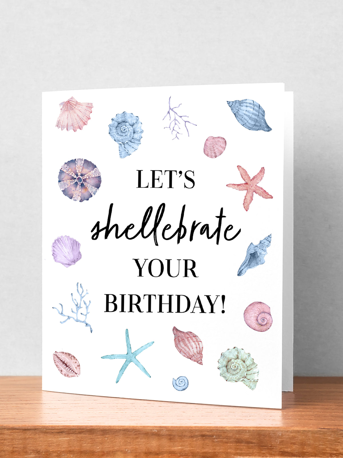 "An artistic depiction of delicate seashells scattered on a sandy beach, accompanied by a vibrant and cheerful birthday card design featuring beach-themed elements, perfect for celebrating a special day by the sea." Light blue pale red, cream colors with Black lettering